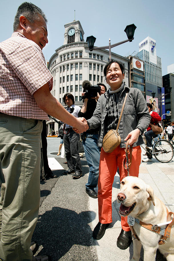 銀座の街を無事に歩き終え、塩屋隆男アイメイト協会代表理事と握手するペア