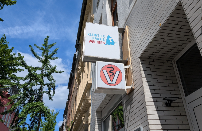 動物病院の看板。赤丸を背景に、「V」字の中に蛇がいるデザインが動物病院のサインです。